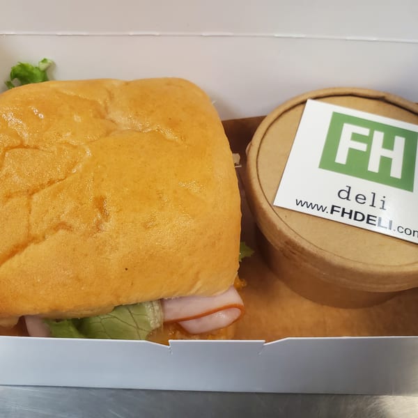 A Field House Deli sandwich and soup in a white takeout box.
